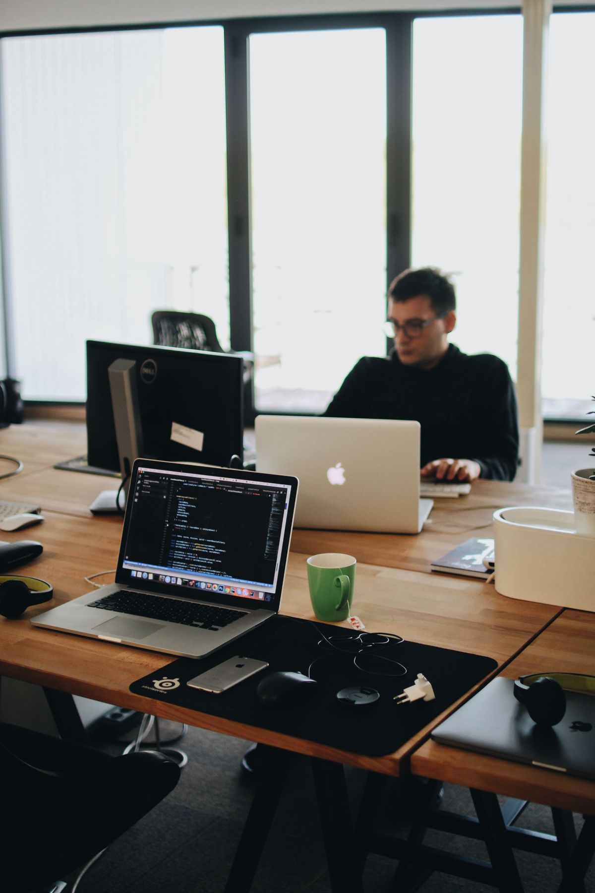 Developer at a multi-monitor workstation writing code—Claude Code and Docker containerized dev environment