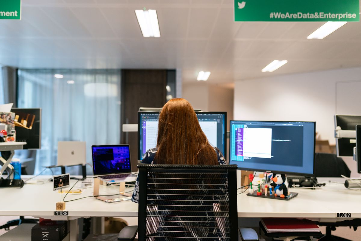 Développeuse devant plusieurs écrans affichant du code et Slack — configuration Claude Code Rules, Skills et Workflow