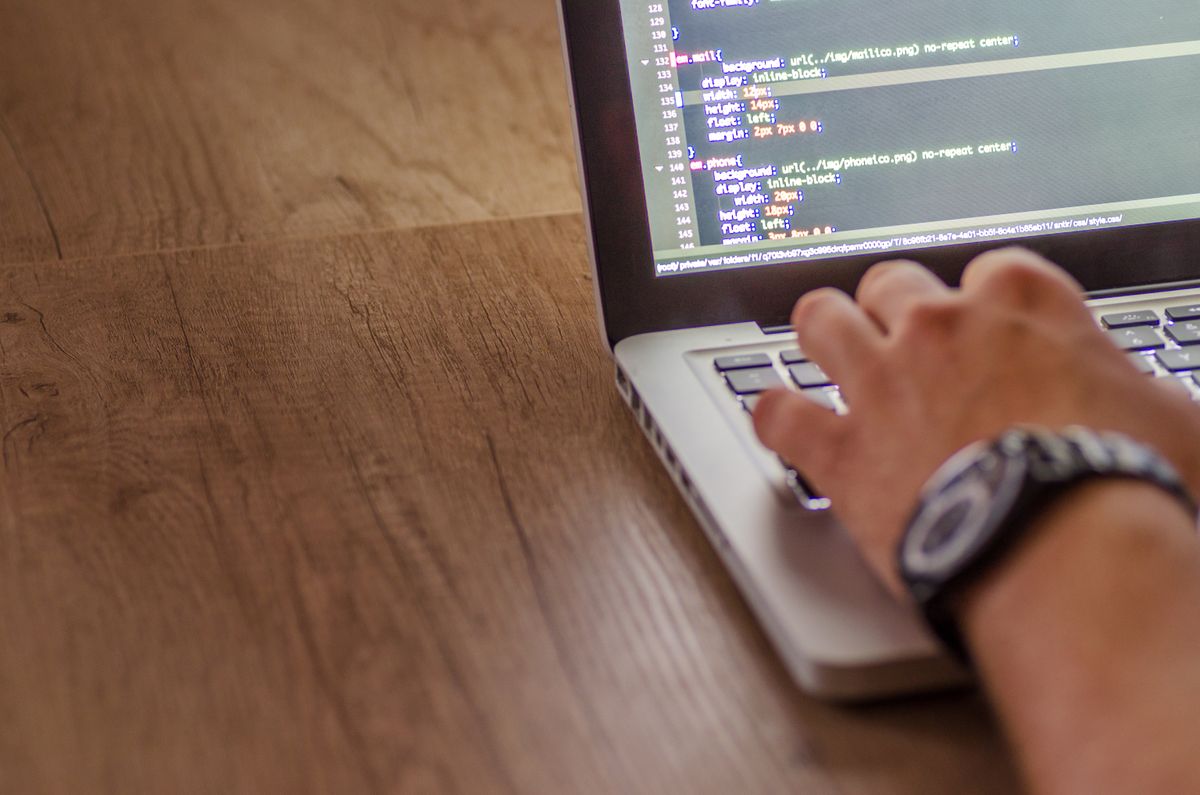 Main sur le clavier d’un laptop affichant du code