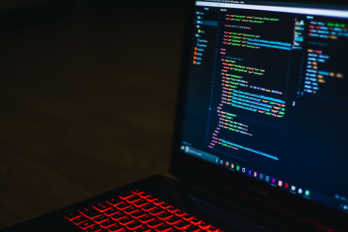 暗い画面のノートPCに HTML とコードエディタが表示されている